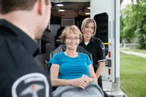 Paramedici assistono paziente sorridente su sedia a rotelle